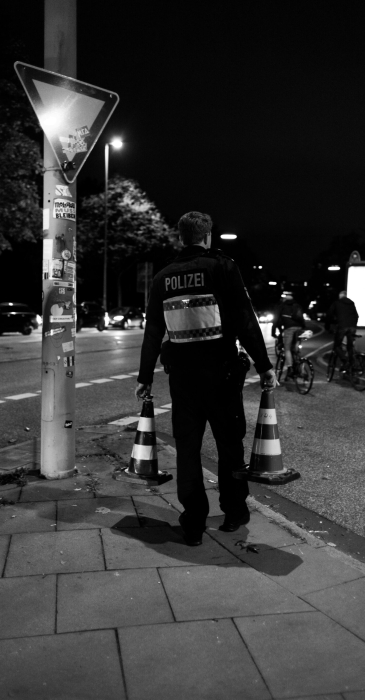Polizist trägt nachts zwei Verkehrshütchen auf einem Gehweg